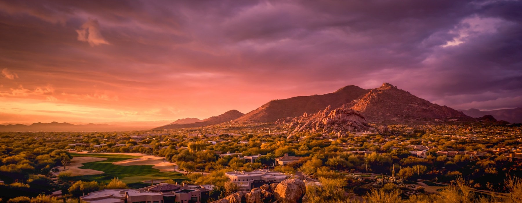 aerial view of a mountain and city with the sunset in the background